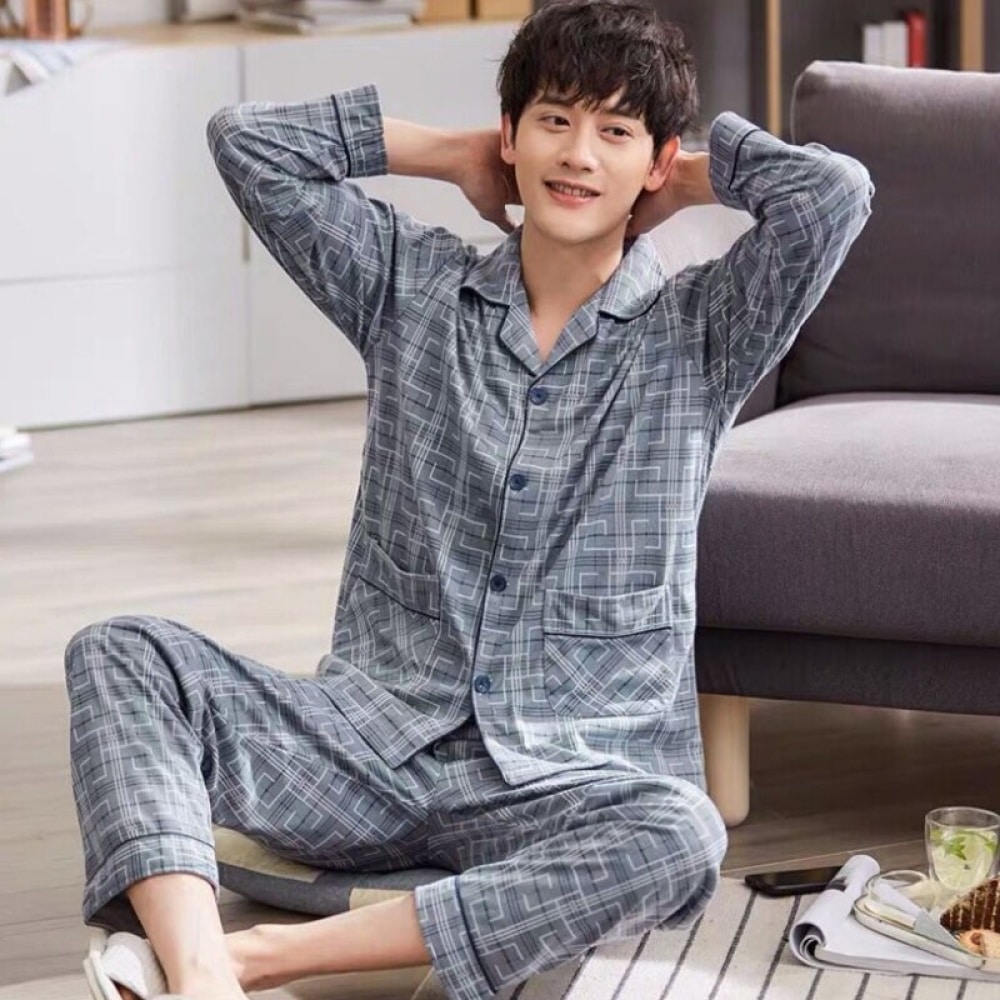 En man som sitter på en matta i ett hus bär en grå pyjamas med geometriskt tryck med flärphals