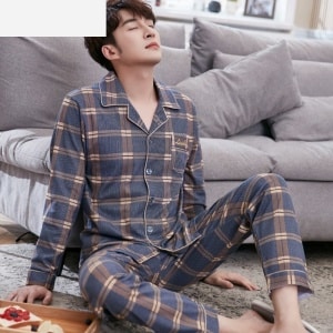 Trendig pyjamas i bomullsrondell för män som bärs av en man som sitter på en matta i ett hus