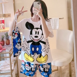 Sommarpyjamas med Micky Mouse-tryck i satin som bärs av en kvinna i ett hus