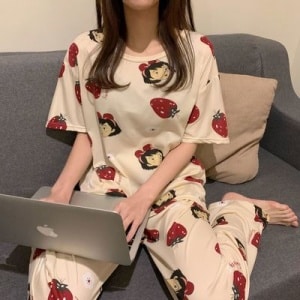 Tvådelad kortärmad pyjamas för kvinnor som bärs av en kvinna som sitter på ett kapell i ett hus