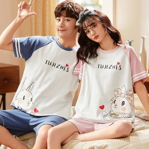 Tvådelad pyjamas i bomullst-shirt och shorts med ett modernt björnmotiv, som bärs av ett par som sitter på en säng i ett hus