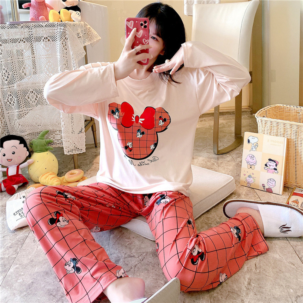 Tvådelad pyjamas i bomull med långa ärmar och Minnie Mouse-design med en flicka i pyjamasen och en bakgrund av ett rum med uppstoppade djur