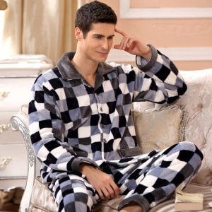 Pyjamas i rutig fleece för män som bärs av en man som sitter i en soffa i ett hus