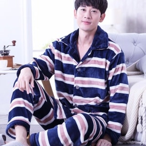 Randig, fodrad pyjamas för män som bärs av en man framför en soffa i ett hus