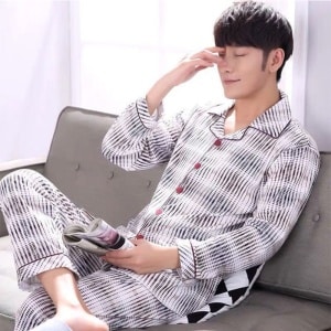 Bomullsrandig pyjamas som bärs av en man som sitter på en stol i ett hus