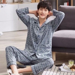 Pyjamas i grå bomullsränder för män som sitter på en matta framför en soffa i ett hus