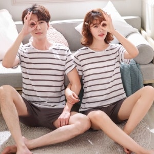 Nattkläder för par med fodrat mönster som bärs av ett par som sitter på en matta i ett hus