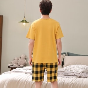 Garfield kortärmad sommarpyjamas för män i gult som bärs av en man framför en säng i ett hus