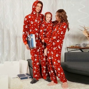 Julpyjamas med huva för hela familjen, som bärs av en familj framför en soffa i ett hus