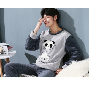Panda pyjamas för män som bärs av en man som sitter i en soffa i ett hus