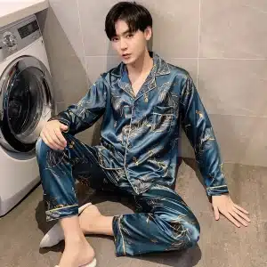 En man som sitter framför en tvättmaskin i ett hus bär en satinblå pyjamas