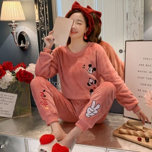 Rosa Musse Pigg-pyjamas för kvinnor som bärs av en kvinna med ett rött pannband i ett fashionabelt hus