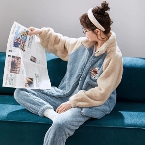 Ljusblå parpyjamas i fleece som bärs av en kvinna som sitter i en soffa i ett hus