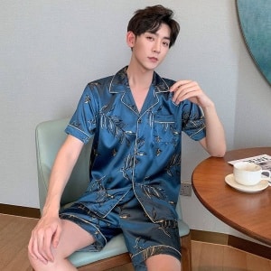 Blå sommarpyjamas i siden för män som bärs av en man som sitter på en stol i ett hus