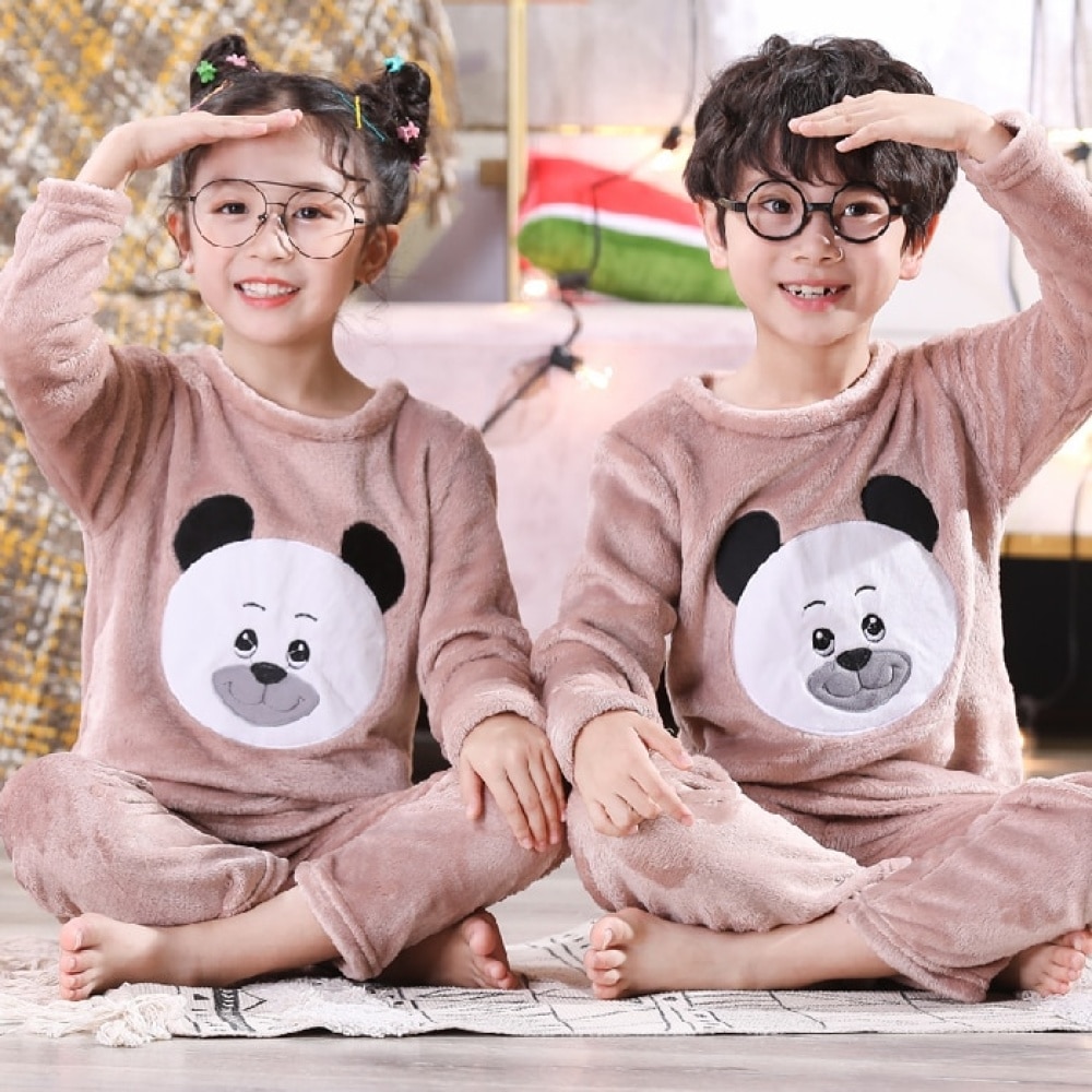 Långärmad flanellpyjamas med pandamönster för barn som bärs av en liten pojke och en liten flicka som sitter på en matta i ett hus