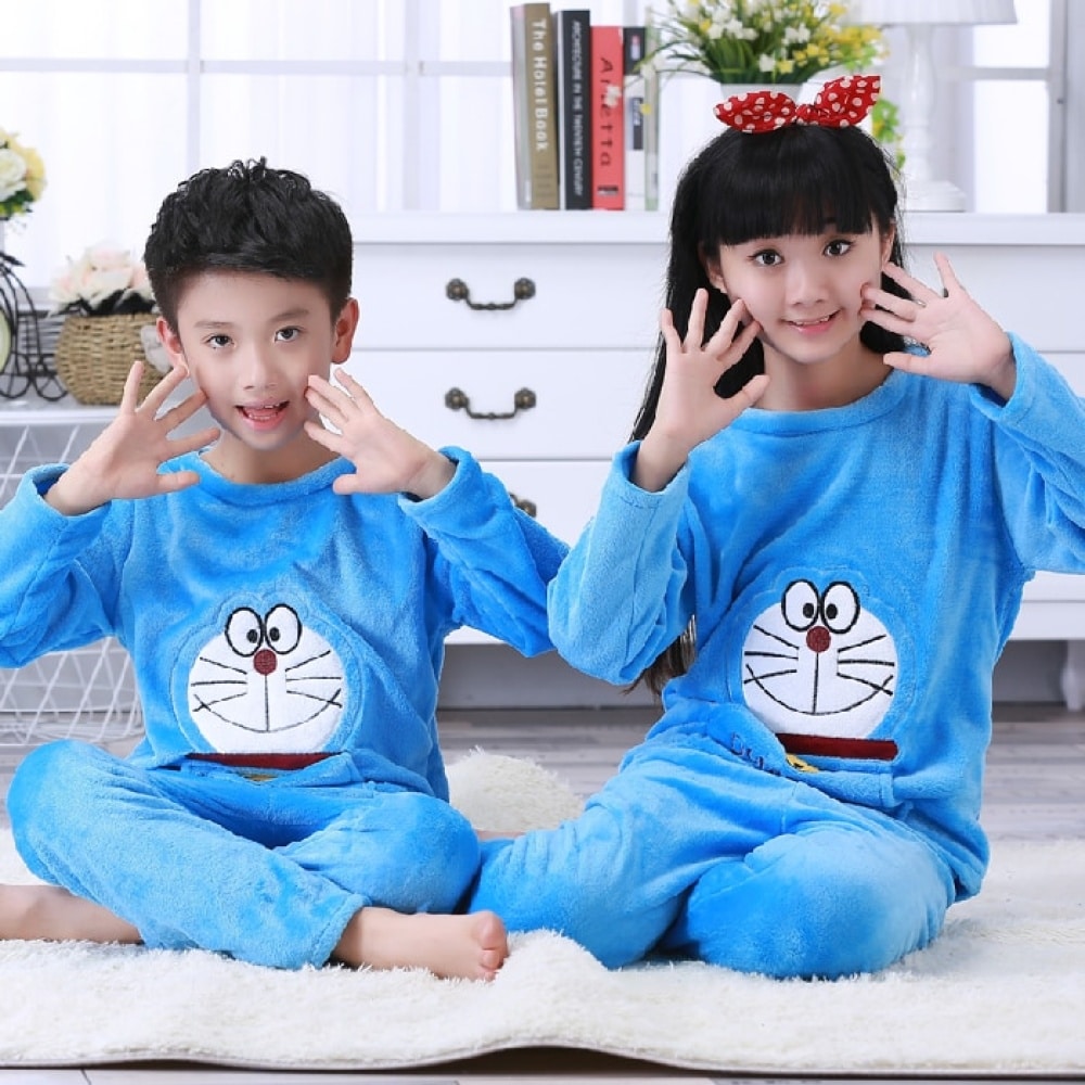 Blå långärmad pyjamas av flanell med Doraemon-tryck för barn som sitter på en matta i ett hus