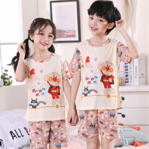 Sommarpyjamas med tecknat motiv för barn som bärs av en liten pojke och en liten flicka i ett hus med en ram som hänger på väggen