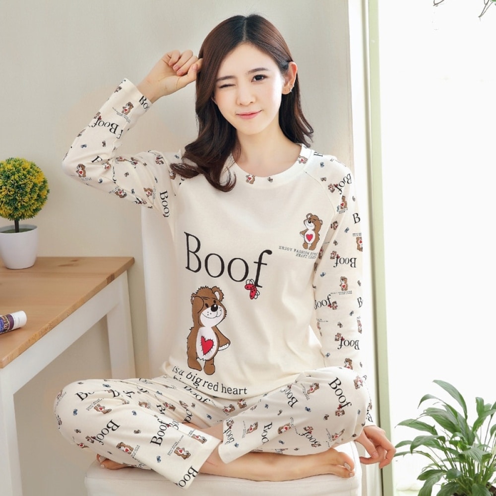 Vit höstpyjamas för kvinnor med Boof-mönster med en bordsbakgrund med en växt och en kvinna som bär pyjamasen