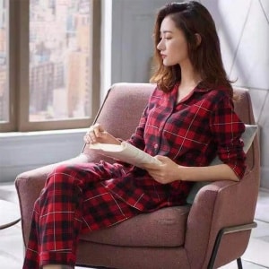 Tvådelad vårpyjamas med rutmönster för kvinnor som bärs av en kvinna som sitter på en stol i ett hus