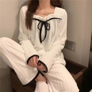 Pyjamas i vit fleece för kvinnor som bärs av en kvinna i ett hus
