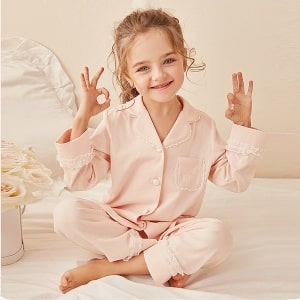 Tvådelad pyjamas i spets för "doing like Mummy" med en liten flicka som bär pyjamasen med en vit spjälsäng och rosa bakgrund