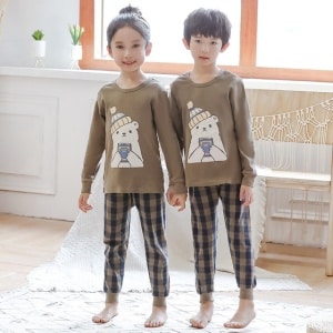Vårpyjamas med beige tröja och rutiga byxor för barn med två barn som bär pyjamas är en bakgrund i ett rum
