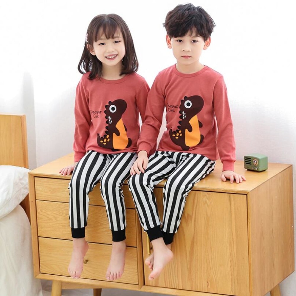 Vårpyjamas med rosa tröja och svartrandiga vita byxor för barn med två barn som bär pyjamas och står på möblerna