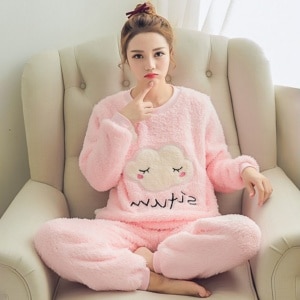 Varm rosa molnig pyjamas med en kvinna i pyjamas i soffan