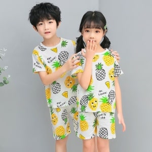 Vit tvådelad pyjamas med ananas med två barn i pyjamasen och grå bakgrund