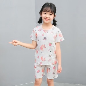 Vit tvådelad pyjamas med tecknat mönster för liten flicka med en liten flicka i pyjamasen och en grå bakgrund