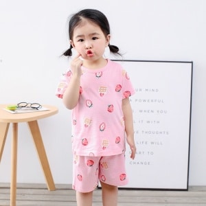 Rosa tvådelad jordgubbspyjamas för småflickor med en söt liten flicka i pyjamasen