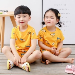 Gul tvådelad pyjamas med tecknat mönster för barn med två små barn som bär pyjamasen