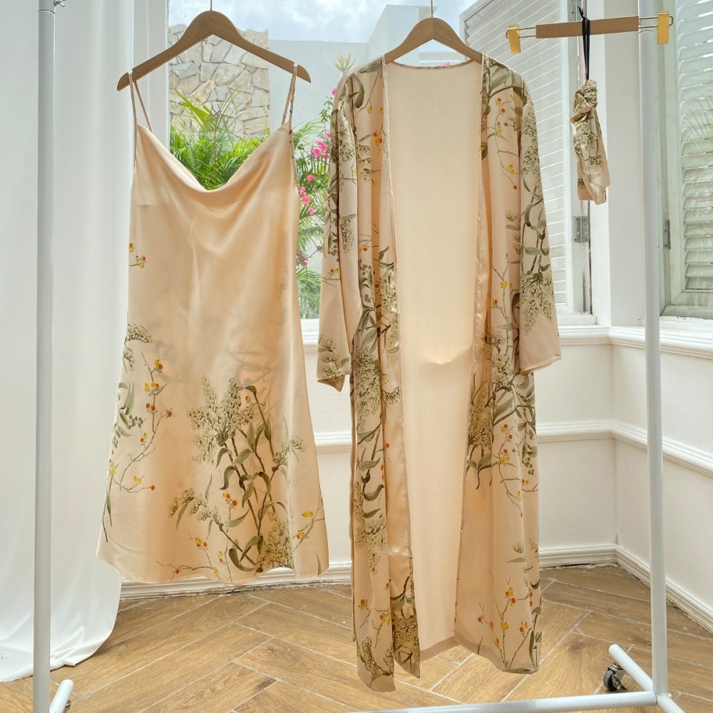 Sexig beige pyjamas med blommönster hängande på galgar i ett rum med trägolv och vit vägg framför ett öppet fönster