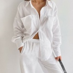 Vit bomullspyjamas som bärs av en kvinna mot en vit vägg