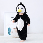 Baby i svart pyjamasdräkt i form av en pingvin tittar på sina fötter